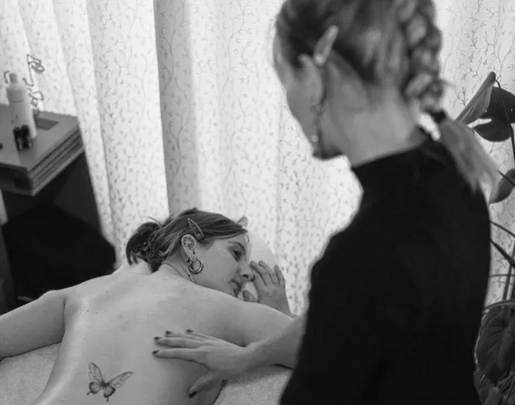 Joy geeft rugmassage aan klant met vlindertatoeage in rustige, lichte salon
