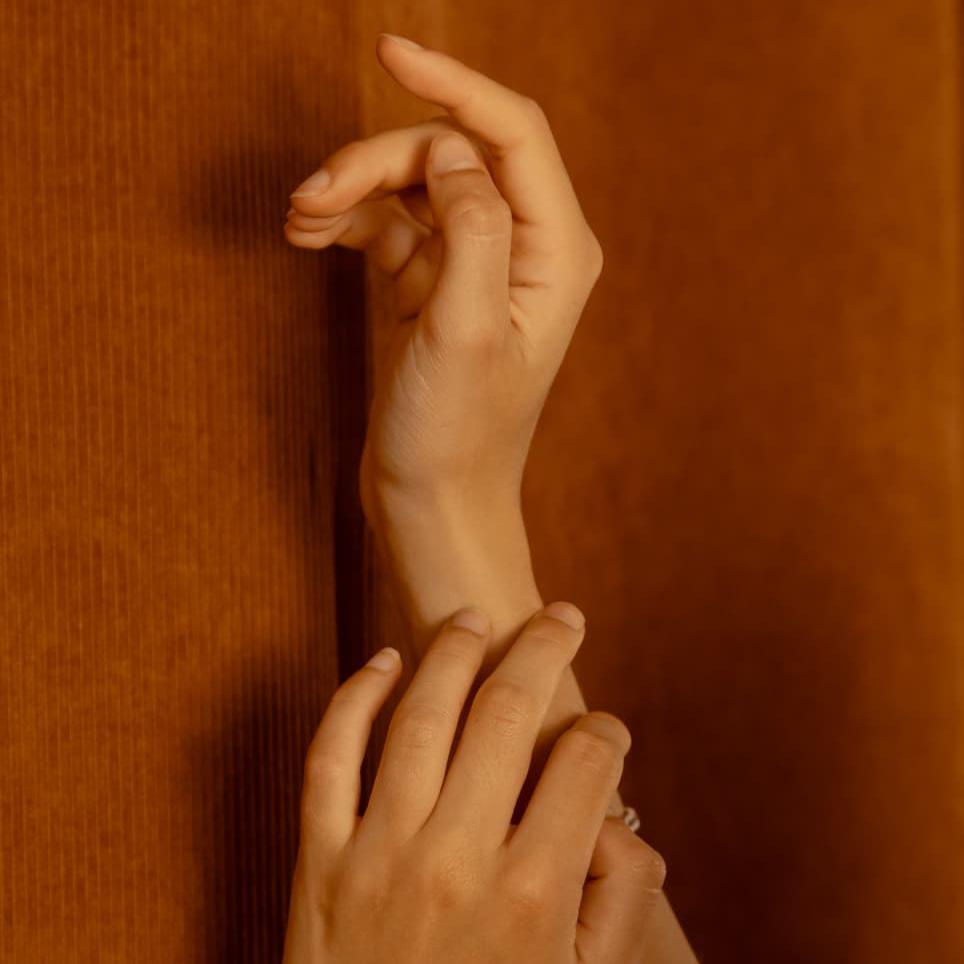 Handen in rusthouding tegen warme bruine achtergrond, detail van mindfulness