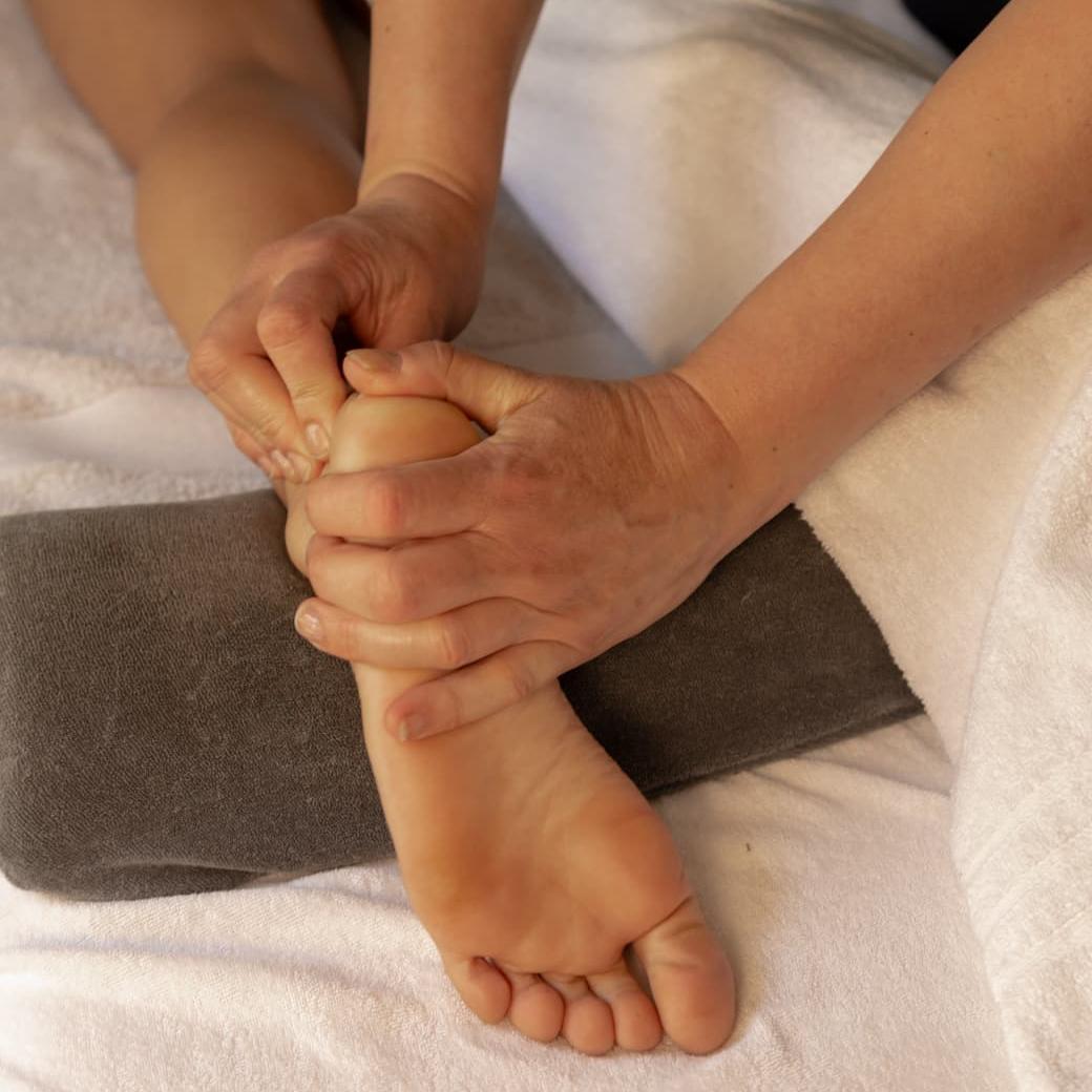 Voetmassage close‑up: Joy kneedt de voetzool boven een steunrol