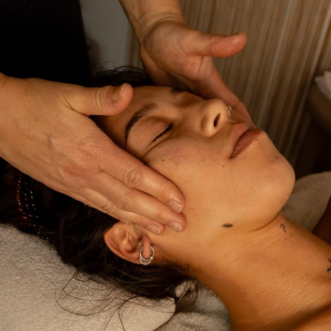 Gezichtsmassage: de masseuse masseert zacht het gezicht van een ontspannen klant